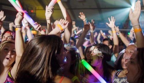 一大群学生拿着荧光棒跳舞，他们的手在空中